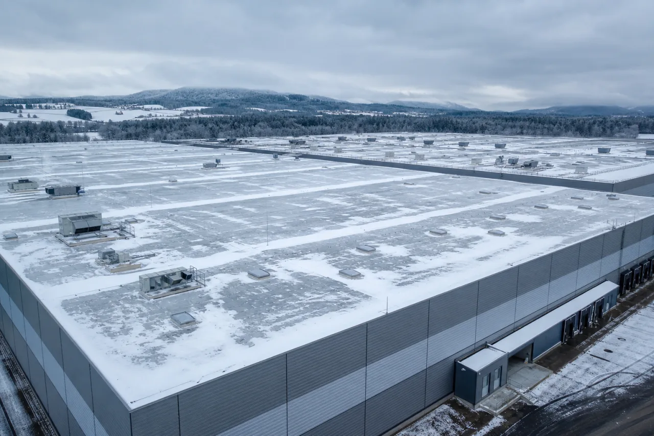 Snow-covered flat roof of a large logistics warehouse in winter